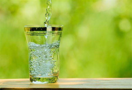 simsearch:400-08815499,k - Pouring Water into a Glass against the Green Nature Background. Space for Text Foto de stock - Royalty-Free Super Valor e Assinatura, Número: 400-06857590