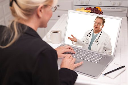 simsearch:400-06857713,k - Woman In Kitchen Using Laptop - Online Chat with Nurse or Doctor on Screen. Fotografie stock - Microstock e Abbonamento, Codice: 400-06857713