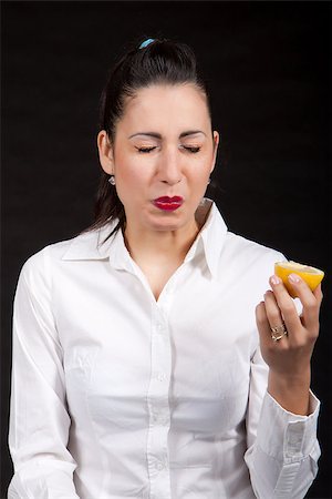 Woman holding in hands yellow lemon and makes a grimace Stock Photo - Budget Royalty-Free & Subscription, Code: 400-06858786