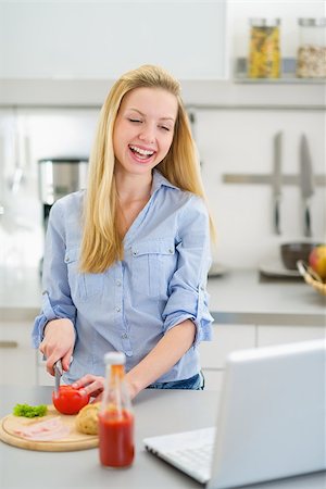 simsearch:400-06929112,k - Happy teenager girl making sandwich in kitchen and looking in laptop Foto de stock - Royalty-Free Super Valor e Assinatura, Número: 400-06853584