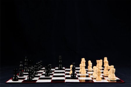 Chessboard with black and white chessman against black background Photographie de stock - Aubaine LD & Abonnement, Code: 400-06864271