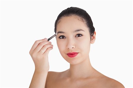 putting on lipstick - Smiling woman filling in eyebrows on white background Stock Photo - Budget Royalty-Free & Subscription, Code: 400-06864720