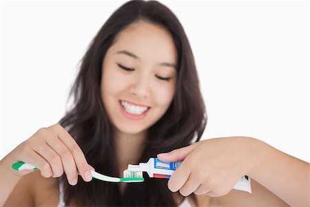 Woman putting toothpaste on toothbrush and smiling Stock Photo - Budget Royalty-Free & Subscription, Code: 400-06864742