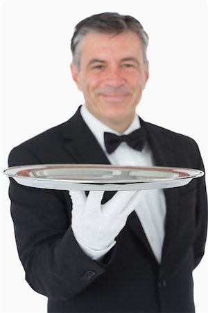 Smiling waiter holding a silver tray in front of camera Fotografie stock - Microstock e Abbonamento, Codice: 400-06865473