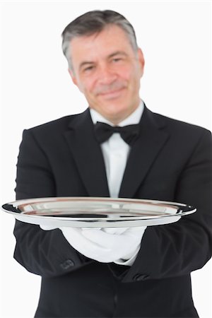 Smiling waiter holding something on a silver tray in front of camera Fotografie stock - Microstock e Abbonamento, Codice: 400-06865496