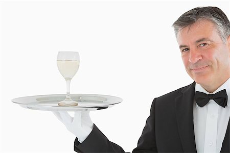 Smiling man in suit serving glass of white wine on silver tray Fotografie stock - Microstock e Abbonamento, Codice: 400-06865529