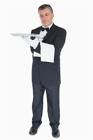 plateau d'argent - Smiling waiter looking at silver tray he is holding Photographie de stock - Aubaine LD & Abonnement, Code: 400-06865614