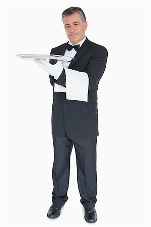 Smiling waiter looking at silver tray he is holding Fotografie stock - Microstock e Abbonamento, Codice: 400-06865614