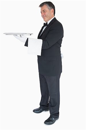 Smiling waiter holding tray and towel over his arm Fotografie stock - Microstock e Abbonamento, Codice: 400-06865616