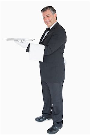 plateau d'argent - Smiling waiter holding silver tray while is looking into the camera Photographie de stock - Aubaine LD & Abonnement, Code: 400-06865617