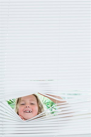 peeking store window - Smiling girl peeking out of white blinds Photographie de stock - Aubaine LD & Abonnement, Code: 400-06865673