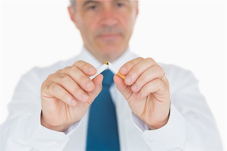 Serious businessman breaking a cigarette in half Stock Photo - Budget Royalty-Free & Subscription, Code: 400-06866382