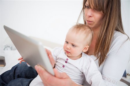 serious mother holding baby - Serious woman holding her baby while using a tablet pc indoors Stock Photo - Budget Royalty-Free & Subscription, Code: 400-06867963