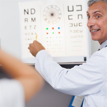 simsearch:400-07630065,k - Doctor smiling while doing an eye test on a patient in a hospital examination room Foto de stock - Super Valor sin royalties y Suscripción, Código: 400-06868010