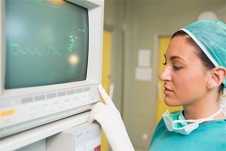 elettrocardiogramma - Smiling female surgeon standing next to a monitor in a surgery room Fotografie stock - Microstock e Abbonamento, Codice: 400-06868037