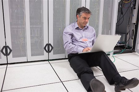 Man sitting on floor of data center using laptop to check the servers Stock Photo - Budget Royalty-Free & Subscription, Code: 400-06868316