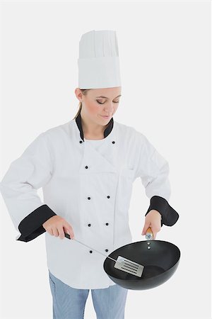 simsearch:400-07953213,k - Female chef holding frying pan and spatula over white background Foto de stock - Super Valor sin royalties y Suscripción, Código: 400-06868715