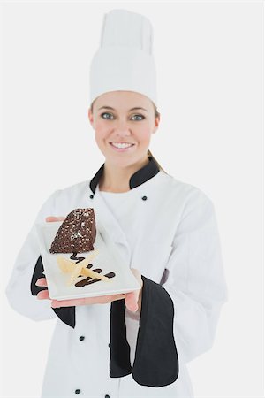 pastry chef uniform for women - Portrait of happy young chef holding plate of pastry over white background Stock Photo - Budget Royalty-Free & Subscription, Code: 400-06868772