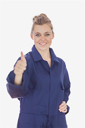 Portrait of happy young female technician witth hand on waist showing thumbs up sign over white background Stockbilder - Microstock & Abonnement, Bildnummer: 400-06868901