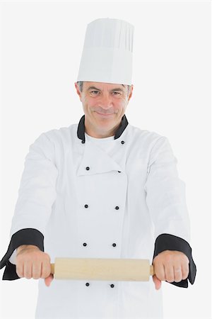 rolling over - Portrait of confident male chef using rolling pin over white background Photographie de stock - Aubaine LD & Abonnement, Code: 400-06869085