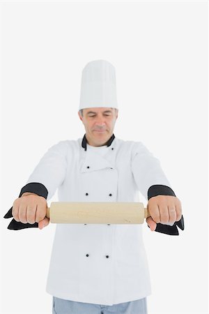 rolling over - Mature male chef holding out rolling pin over white background Photographie de stock - Aubaine LD & Abonnement, Code: 400-06869090