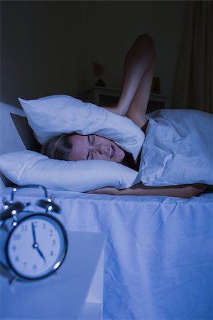 Offended woman putting pillows on her ears at night Stock Photo - Budget Royalty-Free & Subscription, Code: 400-06869259