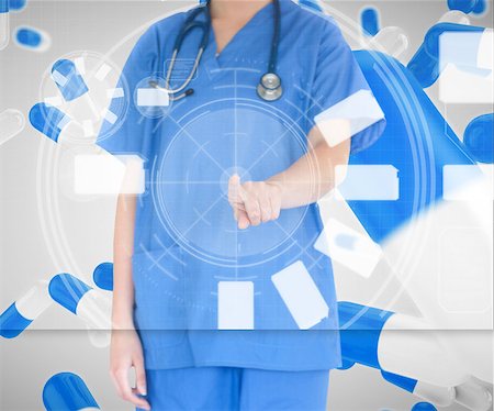 Woman in scrubs using touch screen standing against a pill background Stock Photo - Budget Royalty-Free & Subscription, Code: 400-06869406