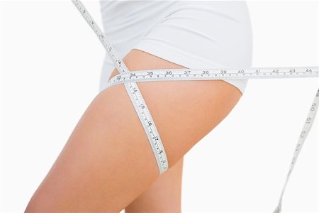 Midsection of fit woman measuring thigh over white background Stock Photo - Budget Royalty-Free & Subscription, Code: 400-06869725