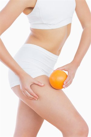 pictures of fat orange women - Fit woman squeezing fat on thigh as she holds orange over white background Stock Photo - Budget Royalty-Free & Subscription, Code: 400-06869737