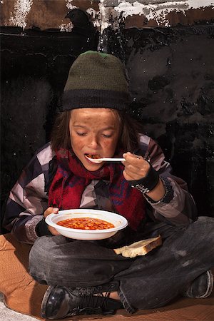 Poor beggar child eating charity food on the street sitting on cardboard plank Stock Photo - Budget Royalty-Free & Subscription, Code: 400-06860468