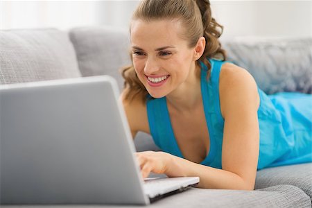 simsearch:400-06419734,k - Smiling young woman laying on couch with laptop Stock Photo - Budget Royalty-Free & Subscription, Code: 400-06861272