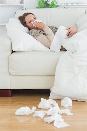 simsearch:400-06801081,k - Sad and sick women lying on the sofa in the living room surrounded by tissues Photographie de stock - Aubaine LD & Abonnement, Code: 400-06862812