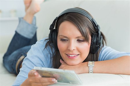 simsearch:400-04418454,k - Happy woman listening music looking at cd on sofa in the living room Stockbilder - Microstock & Abonnement, Bildnummer: 400-06862839