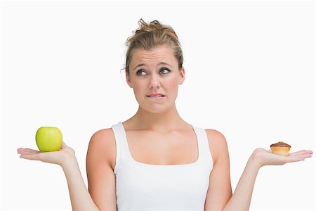 Woman holding apple and cupcake deciding to eat healthily or not Stock Photo - Budget Royalty-Free & Subscription, Code: 400-06862955
