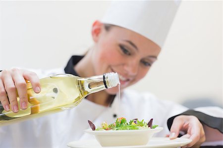 simsearch:400-06863053,k - Smiling woman chef dressing a salad in the kitchen Stockbilder - Microstock & Abonnement, Bildnummer: 400-06862982