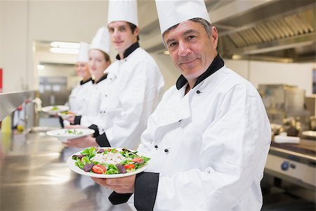 simsearch:400-06863053,k - Cheerful Chef's showing their salads in the kitchen Stockbilder - Microstock & Abonnement, Bildnummer: 400-06863011