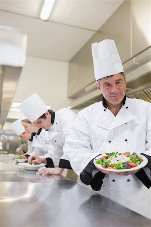 simsearch:400-06863053,k - Cheerful chef showing his salad with workers in background in the kitchen Stockbilder - Microstock & Abonnement, Bildnummer: 400-06863020