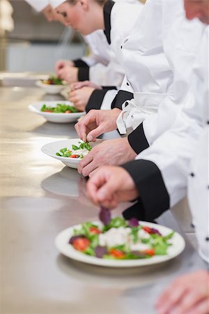 simsearch:400-06863053,k - Concentrated Chef's team garnishing salads in the kitchen Stockbilder - Microstock & Abonnement, Bildnummer: 400-06863038