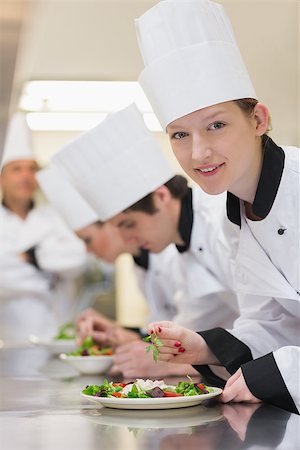 simsearch:400-06863053,k - Smiling chef looking up from preparing salad in culinary class Stockbilder - Microstock & Abonnement, Bildnummer: 400-06863030