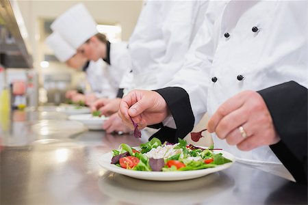 simsearch:400-06863053,k - Chef garnishing salads in the kitchen with others garnishing their salads Stockbilder - Microstock & Abonnement, Bildnummer: 400-06863041