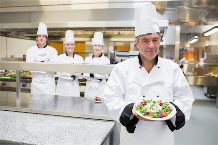 simsearch:400-06863053,k - Head chef presenting salad with his team standing behind him Stockbilder - Microstock & Abonnement, Bildnummer: 400-06863057