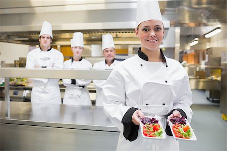 simsearch:400-06863053,k - Chef presenting two salads in kitchen with team standing behind her Stockbilder - Microstock & Abonnement, Bildnummer: 400-06863059