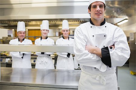 simsearch:400-06863195,k - Male chef standing in kitchen with team behind him Foto de stock - Super Valor sin royalties y Suscripción, Código: 400-06863064