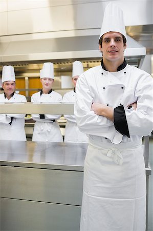 simsearch:400-06863195,k - Chef standing with arms crossed with team behind him in the kitchen Foto de stock - Super Valor sin royalties y Suscripción, Código: 400-06863065