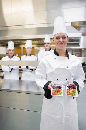 simsearch:400-06863053,k - Chef presenting her salads in kitchen with team behind her Stockbilder - Microstock & Abonnement, Bildnummer: 400-06863060