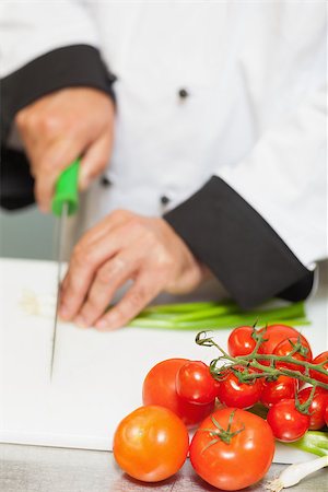 simsearch:649-08766085,k - Chef chopping spring onions on counter with tomatoes Photographie de stock - Aubaine LD & Abonnement, Code: 400-06863090