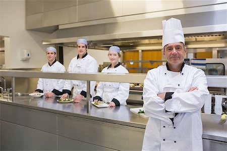 simsearch:400-06863195,k - Head chef standing smiling with team behind him in the kitchen Foto de stock - Super Valor sin royalties y Suscripción, Código: 400-06863176