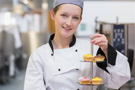 pastry chef uniform for women - Happy chef holding tiered cake tray of cupcakes in kitchen Stock Photo - Budget Royalty-Free & Subscription, Code: 400-06863330
