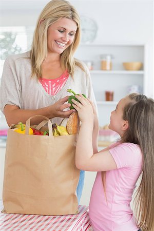 Woman giving green pepper to daughter from grocery bag in the kitchen Stock Photo - Budget Royalty-Free & Subscription, Code: 400-06863521