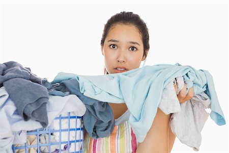 dirty clothes hamper - Frowning young woman taking out the dirty laundry from the basket Stock Photo - Budget Royalty-Free & Subscription, Code: 400-06863700
